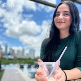 a woman smiling holding a plastic cup with a straw