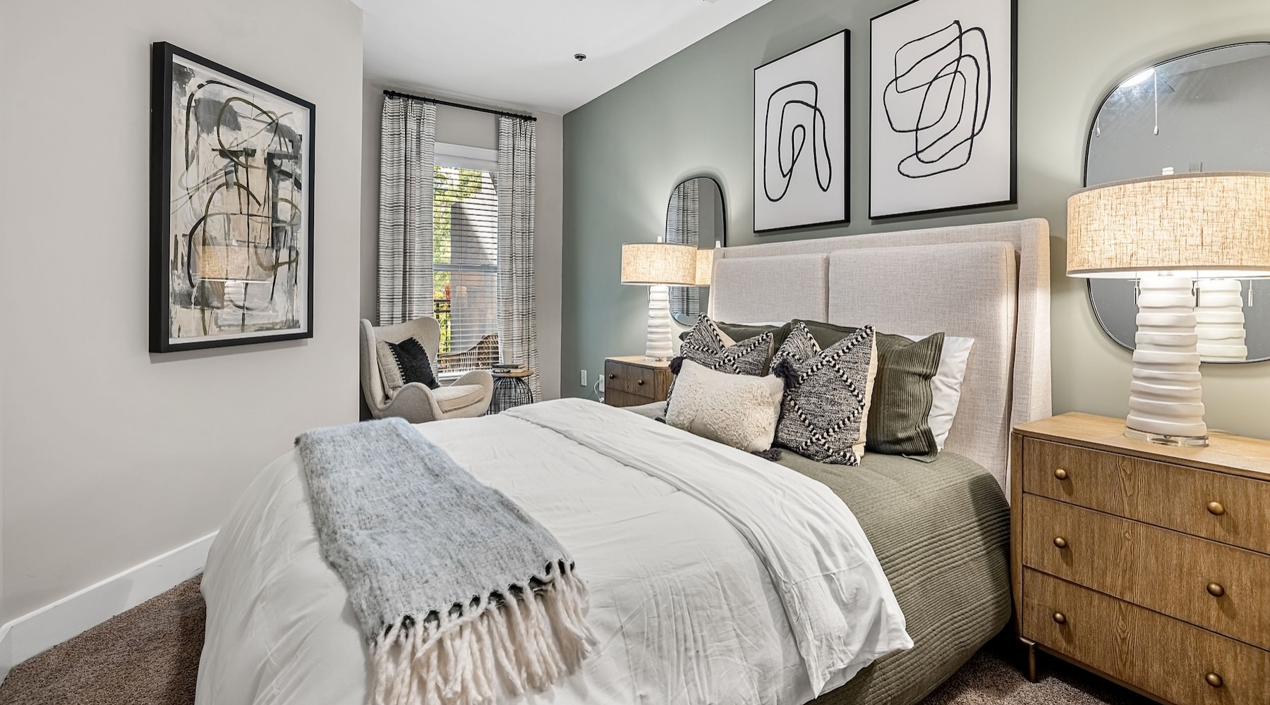 bedroom with art on the walls and a large bed with a nightstand and lamp