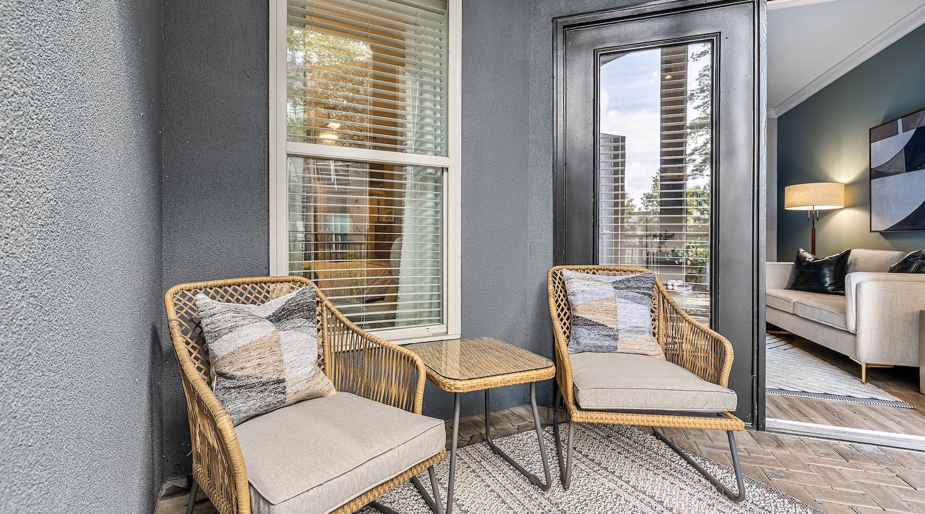 patio with two chairs and a table and a glass door to a living room in the background
