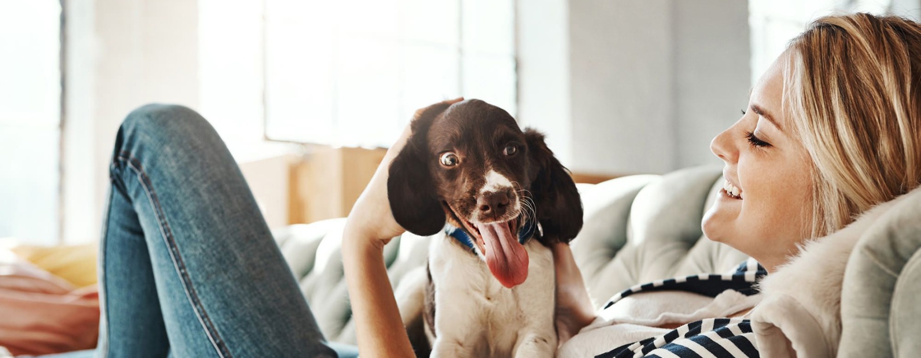 woman lies on a couch and pets her dog